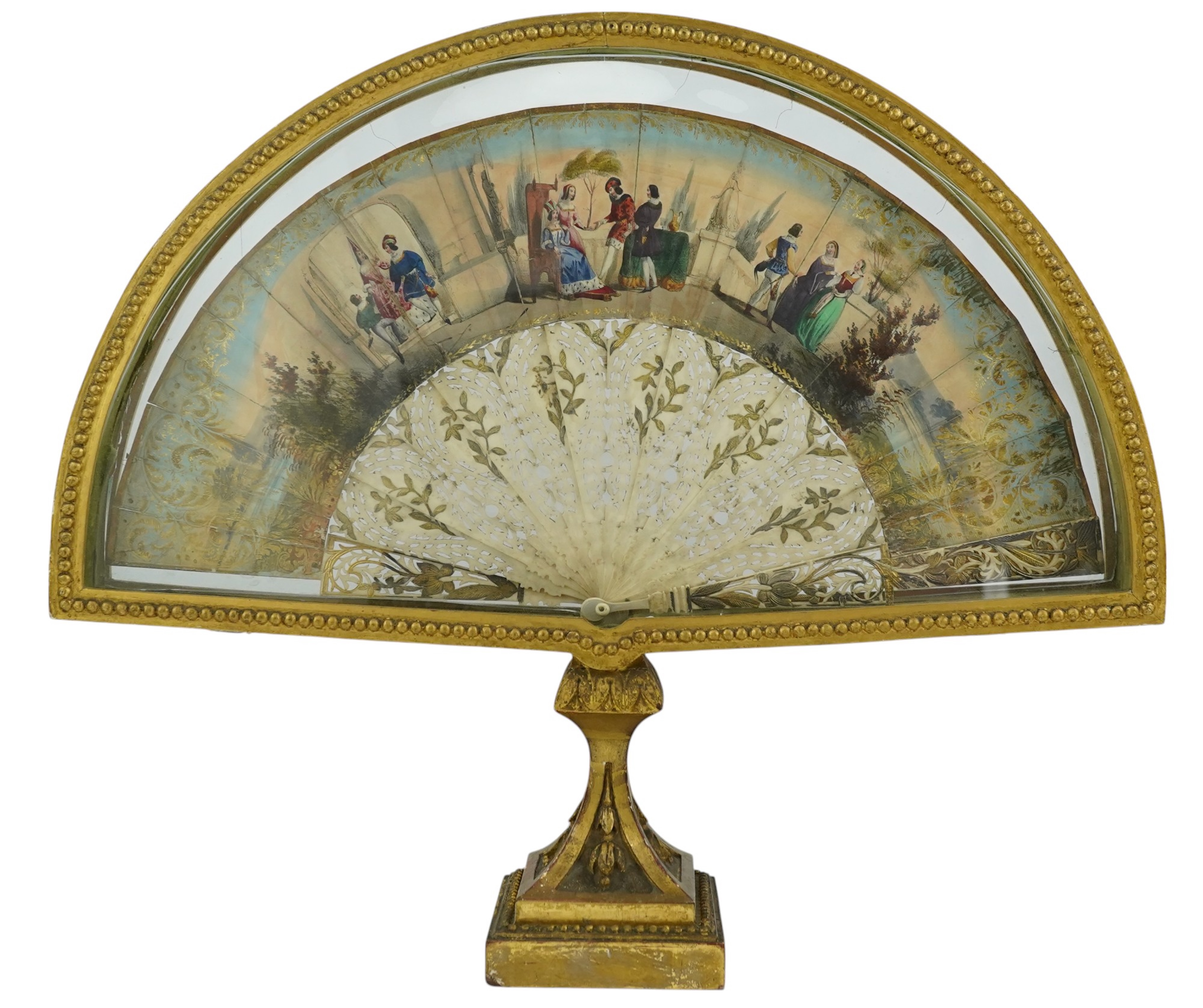 Two giltwood fans and display cases, one on a pedestal base housing an 18th century French figural hand painted fan with bone and gilt decorated guards and sticks, the other set with paste gilt metal guards on mother of